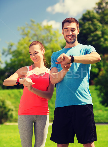 Stock photo: smiling people with heart rate watches outdoors