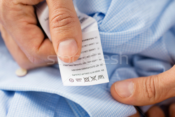 close up of male hands holding shirt and label Stock photo © dolgachov