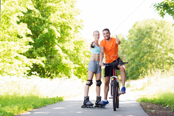 couple on rollerblades and bike showing thumbs up Stock photo © dolgachov