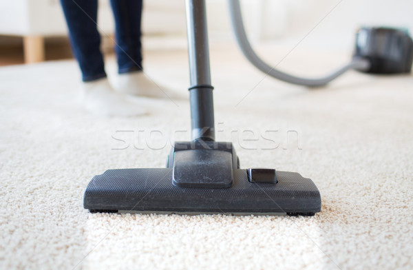 Stock photo: close up of woman legs with vacuum cleaner at home