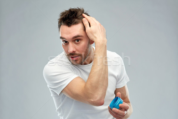 happy young man styling his hair with wax or gel Stock photo © dolgachov