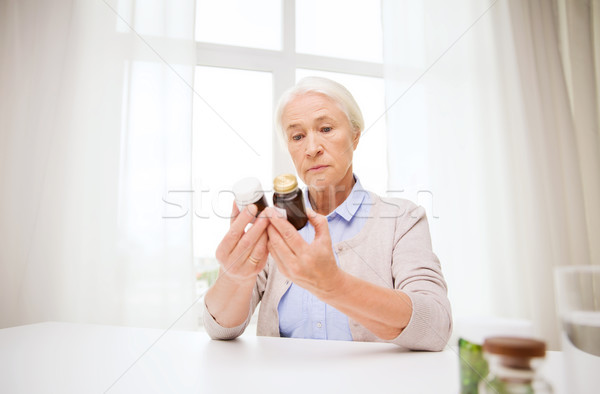 senior woman with medicine jars at home Stock photo © dolgachov