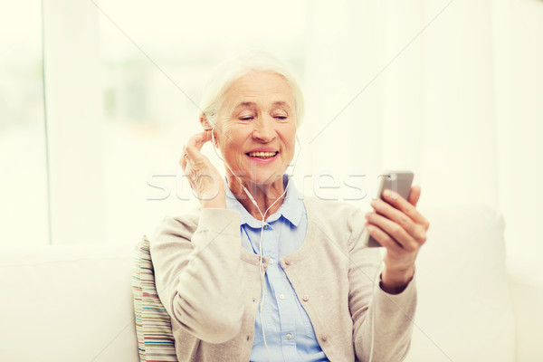 senior woman with smartphone and earphones at home Stock photo © dolgachov