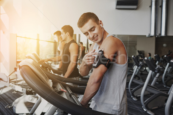 man with smartphone exercising on treadmill in gym Stock photo © dolgachov