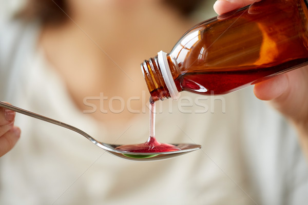 woman pouring medication from bottle to spoon Stock photo © dolgachov