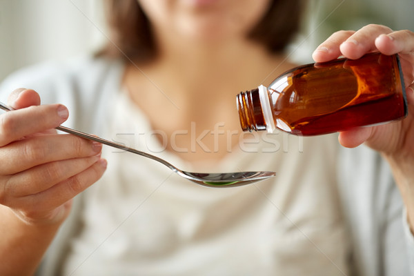 woman pouring medication from bottle to spoon Stock photo © dolgachov