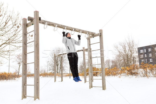 Stock photo: young man exercising on horizontal bar in winter