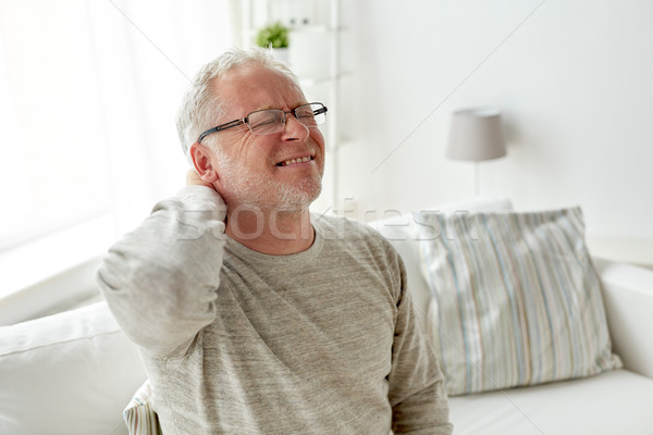 senior man suffering from neckache at home Stock photo © dolgachov