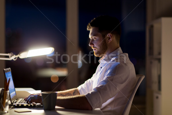 man with laptop and coffee working at night office Stock photo © dolgachov