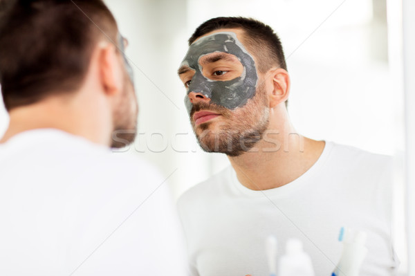 Fiatalember agyag maszk arc fürdőszoba bőrápolás Stock fotó © dolgachov