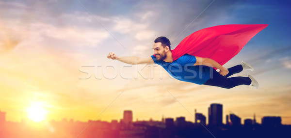 happy man in red superhero cape flying over city Stock photo © dolgachov