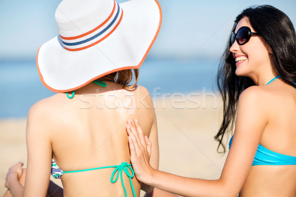 girls applying sun cream on the beach Stock photo © dolgachov