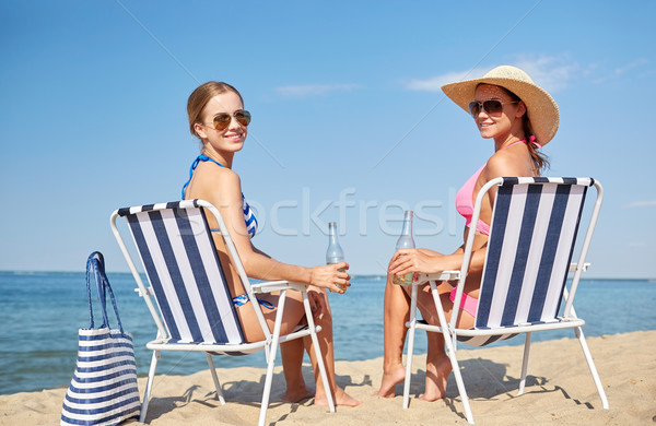 happy women sunbathing in lounges on beach Stock photo © dolgachov