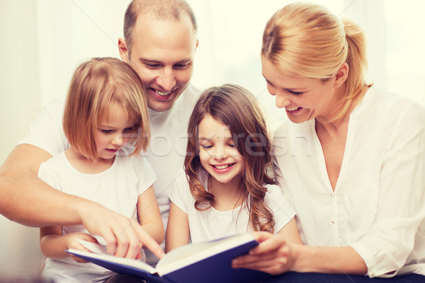smiling family and two little girls with book Stock photo © dolgachov