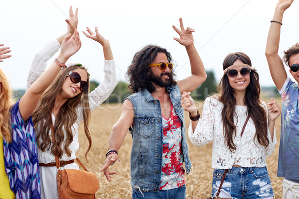 happy young hippie friends dancing on cereal field Stock photo © dolgachov