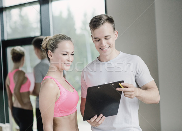 smiling young woman with personal trainer in gym Stock photo © dolgachov