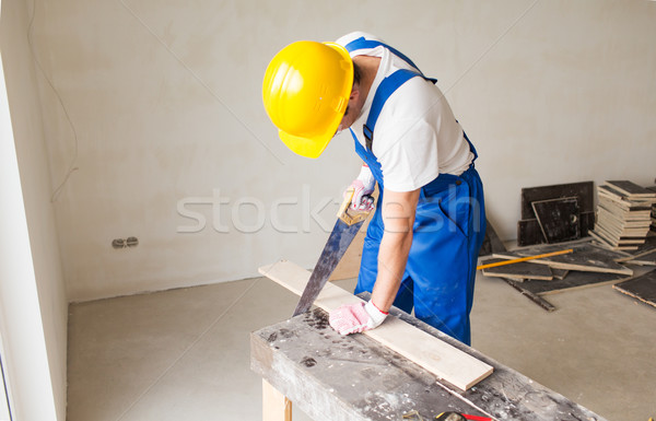 close up of builder with arm saw sawing board Stock photo © dolgachov