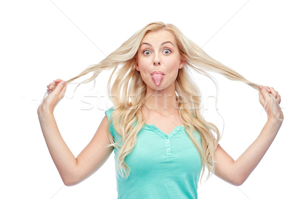 happy young woman showing tongue and holding hair Stock photo © dolgachov