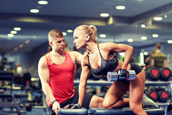 young couple with dumbbell flexing muscles in gym Stock photo © dolgachov