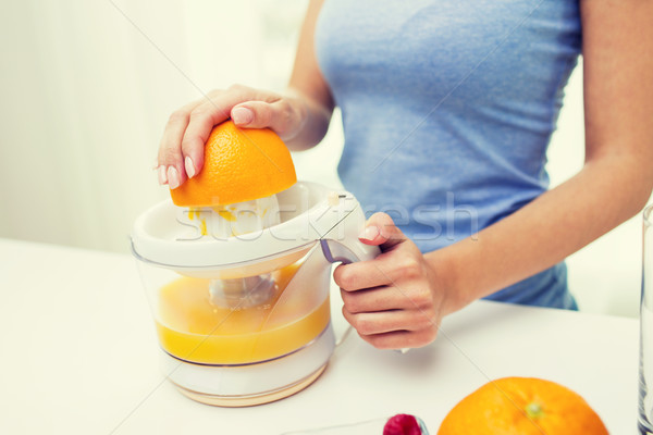 Stock photo: close up of woman squeezing orange juice at home