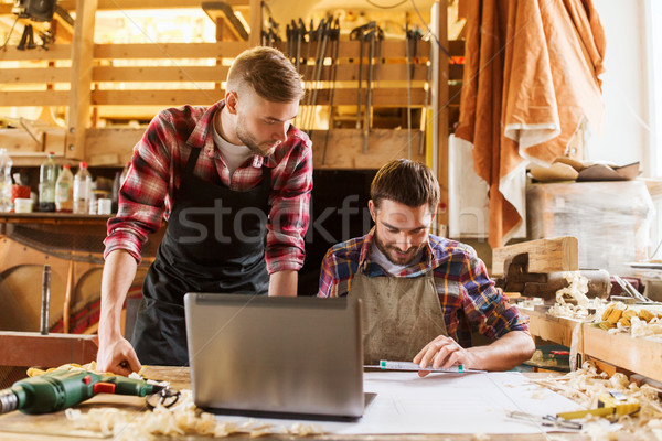 carpenters with laptop and blueprint at workshop Stock photo © dolgachov