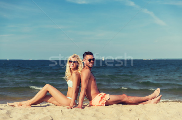 happy couple in swimwear sitting on summer beach Stock photo © dolgachov