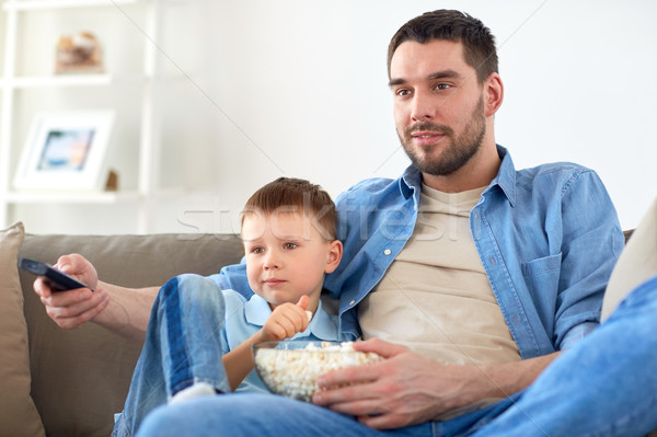 Tata fiu floricele de porumb vizionarea televizor acasă familie Imagine de stoc © dolgachov