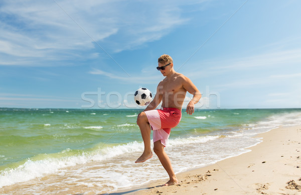 young man with ball playing soccer on beach Stock photo © dolgachov
