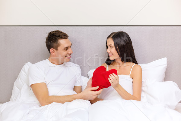 smiling couple in bed with red heart shape pillow Stock photo © dolgachov