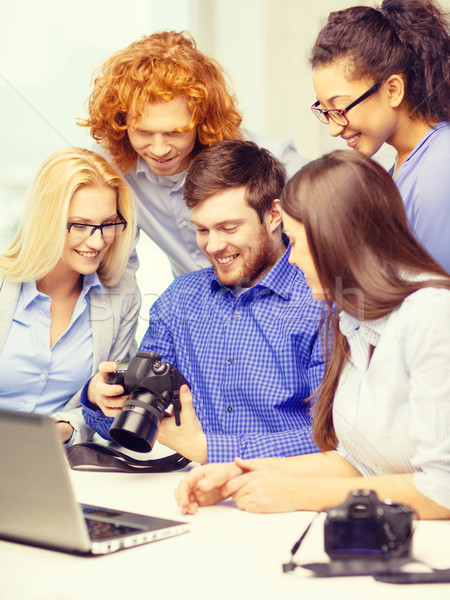 smiling team with laptop and photocamera in office Stock photo © dolgachov