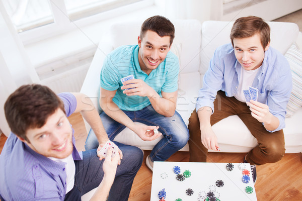 Drie glimlachend mannelijke vrienden speelkaarten home Stockfoto © dolgachov