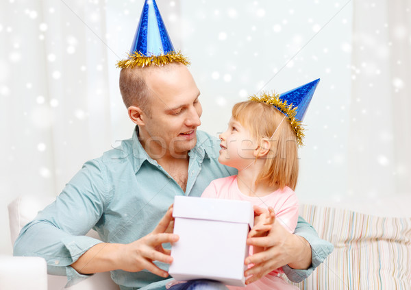 father and daughter in party caps with gift box Stock photo © dolgachov