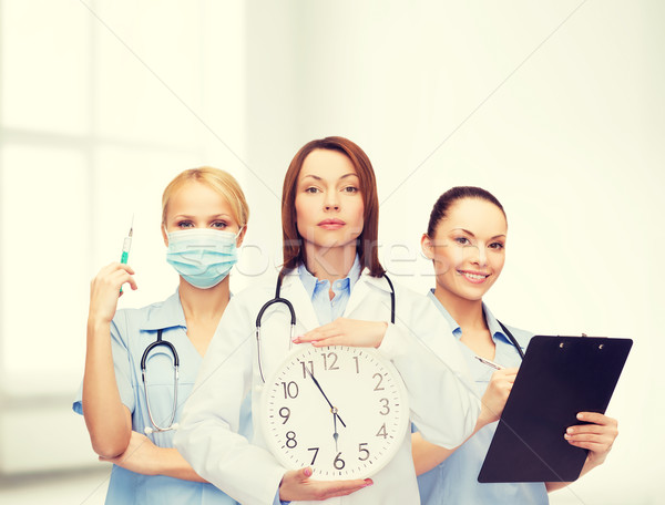 calm female doctor and nurses with wall clock Stock photo © dolgachov