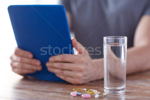 close up of hands with tablet pc, pills and water Stock photo © dolgachov