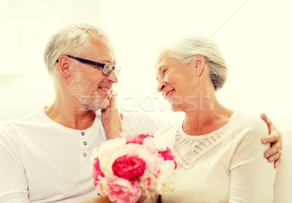 Stock photo: happy senior couple with bunch of flowers at home