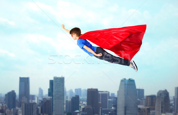 Stock photo: boy in red superhero cape and mask flying on air