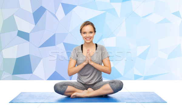 woman making yoga meditation in lotus pose on mat Stock photo © dolgachov