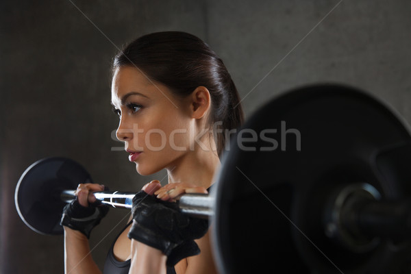 young woman flexing muscles with barbell in gym Stock photo © dolgachov