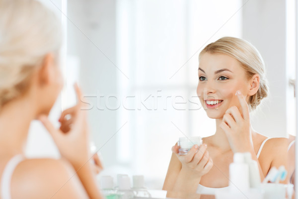 Heureux femme crème visage salle de bain [[stock_photo]] © dolgachov