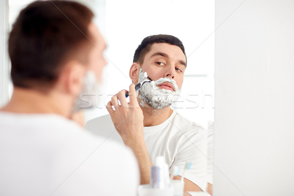 man shaving beard with razor blade at bathroom Stock photo © dolgachov