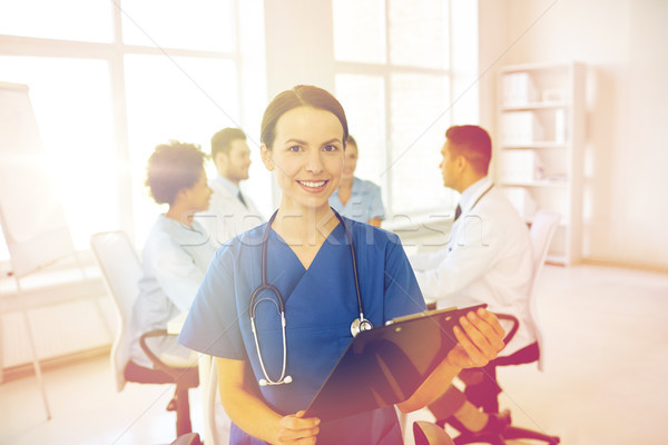 Stock photo: happy doctor with clipboard over group of medics