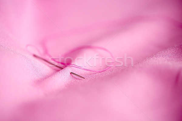 sewing needle with thread stuck into pink fabric Stock photo © dolgachov