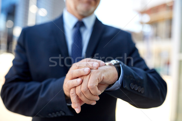 senior businessman with wristwatch on city street Stock photo © dolgachov