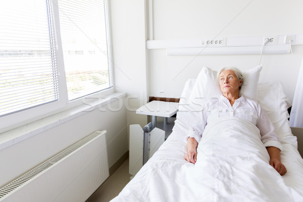 sad senior woman lying on bed at hospital ward Stock photo © dolgachov
