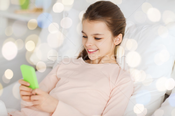 Boldog lány ágy okostelefon fények emberek gyerekek Stock fotó © dolgachov