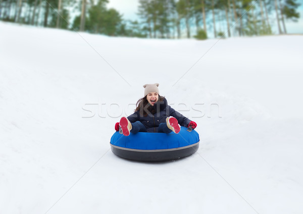 Stock photo: happy teenage girl sliding down on snow tube