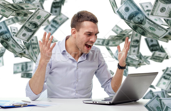angry businessman with laptop and falling money Stock photo © dolgachov