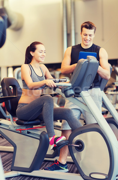 happy woman with trainer on exercise bike in gym Stock photo © dolgachov