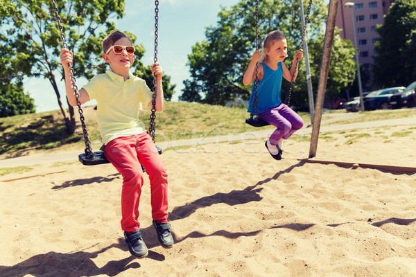 two happy kids swinging on swing at playground Stock photo © dolgachov