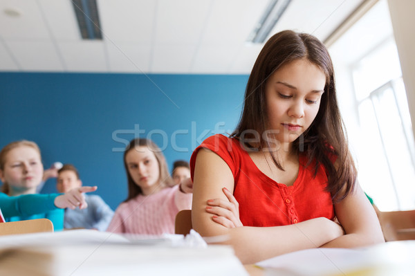 Stock photo: students gossiping behind classmate back at school